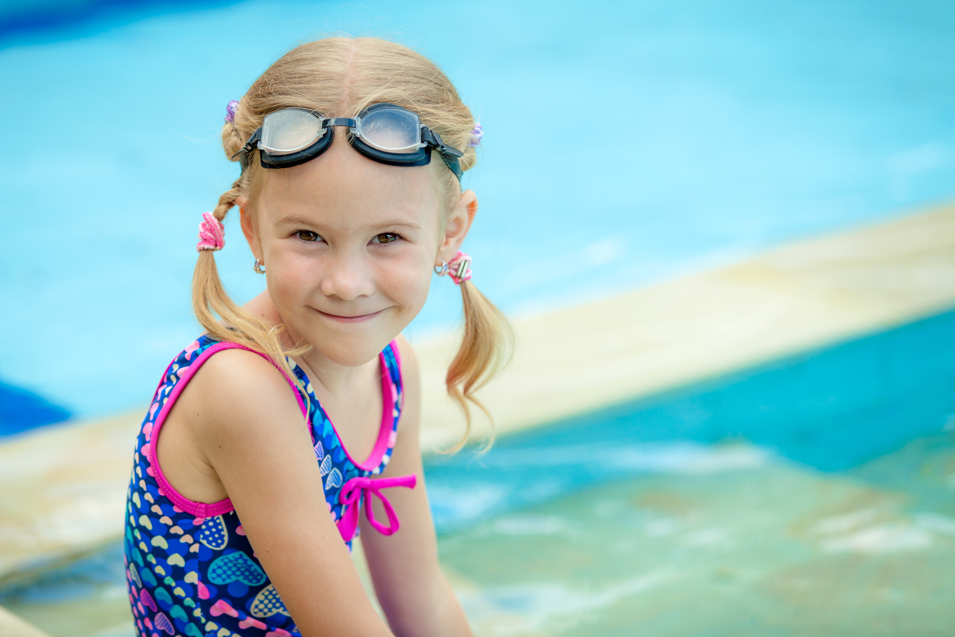 little girl sitting near swimming pool